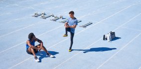 Молодые бегуны на солнечно-голубом спортивном треке — стоковое фото