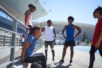 Бігун і друзі-ампутатори розмовляють на сонячній спортивній трасі — стокове фото