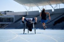 Allenamento di atleti su sedia a rotelle sulla pista sportiva blu soleggiata — Foto stock