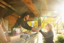 Glücklicher Foodtruck-Besitzer serviert Kunden im sonnigen Park Essen — Stockfoto