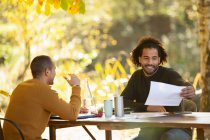 Empresarios discutiendo papeleo en la mesa en el parque de otoño - foto de stock