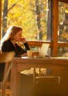 Geschäftsfrau arbeitet am Laptop in sonnigem Café — Stockfoto