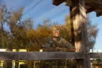 Femme réfléchie regardant les arbres par la fenêtre du restaurant — Photo de stock