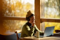 Geschäftsfrau mit Kopfhörer arbeitet am Laptop im Café — Stockfoto