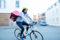 Hombre mensajero de bicicleta entrega de alimentos en bicicleta en el barrio urbano - foto de stock