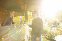 Власник продовольчої вантажівки та клієнт розмовляють у сонячному осінньому парку — стокове фото