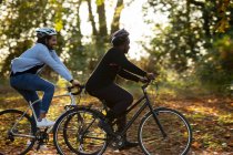 Freunde fahren mit Fahrrädern durch Herbstlaub im Park — Stockfoto