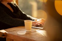 Mulher com café trabalhando no laptop na mesa de café — Fotografia de Stock