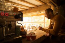 Male cafe owner using digital tablet behind counter — Stock Photo