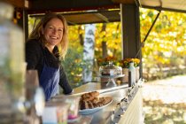 Portrait happy female food cart owner working in park — Stock Photo
