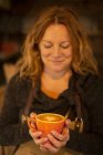 Joyeuse femme barista tenant cappuccino avec mousse en forme de coeur — Photo de stock