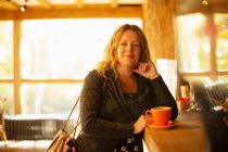 Portrait happy woman ordering cappuccino at cafe counter — Stock Photo