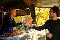 Friendly food cart owner serving customer — Stock Photo