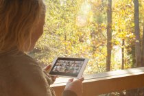 Frau chattet mit Freunden auf digitalem Tablet am Fenster — Stockfoto