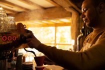 Maschio barista preparare cappuccino alla macchina da caffè espresso in caffè — Foto stock