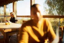 Geschäftsfrau mit Kopfhörer arbeitet in sonnigem Herbstcafé — Stockfoto