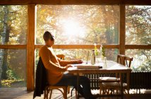 Geschäftsmann mit Kopfhörer am Laptop im sonnigen Herbstcafé — Stockfoto