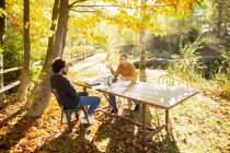 Hombres de negocios reunidos en la mesa en el idílico parque de otoño - foto de stock