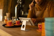 Männlicher Barista nutzt digitales Tablet am Café-Tresen — Stockfoto