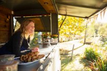 Happy female food cart owner in sunny autumn park — Stock Photo