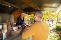 Proprietario amichevole del carrello del cibo che serve caffè al cliente nel parco autunnale — Foto stock