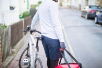 Male bike messenger delivering food on urban street — Stock Photo