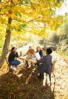 Empresários com reunião de papelada à mesa no ensolarado parque de outono — Fotografia de Stock