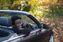 Portrait happy woman driving convertible in autumn park — Stock Photo