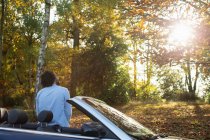 Hombre en convertible en soleado parque de otoño - foto de stock