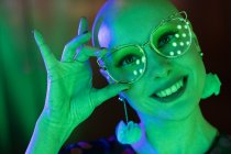 De cerca retrato mujer feliz con gafas retro en luz verde - foto de stock