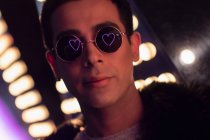 Portrait jeune homme cool avec reflet coeur néon dans les lunettes de soleil — Photo de stock