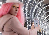 Portrait woman with pink hair and smart phone photo of arch lights — Stock Photo