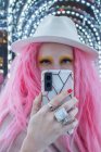 Portrait cool stylish woman with pink hair and fedora taking selfie — Stock Photo