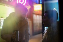 Happy couple with coffee waiting at bus stop in city at night — Stock Photo