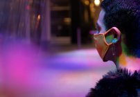 Elegante jovem com pino de segurança brinco usando máscara sob néon — Fotografia de Stock