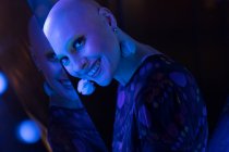 Ritratto bella donna con testa rasata in luce blu al neon — Foto stock