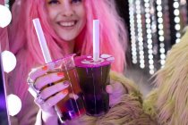 Щаслива стильна жінка з рожевим волоссям тримає коктейлі в одноразовій чашці — стокове фото