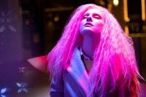 Belle femme avec les cheveux roses et la tête de retour sous la lumière — Photo de stock
