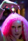 Portrait femme cool avec des cheveux roses tenant ampoule au-dessus de la tête — Photo de stock