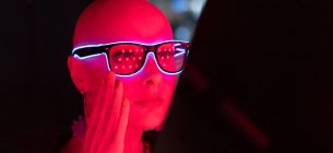 Ritratto donna elegante con la testa rasata in occhiali al neon a luce rossa — Foto stock
