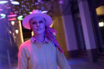 Portrait fashionable woman in fedora under neon lights — Stock Photo