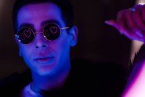 Портрет прохладный молодой человек в солнечных очках с отражением сердца в темноте — стоковое фото