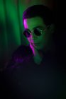 Stylish young man wearing sunglasses in dark — Stock Photo