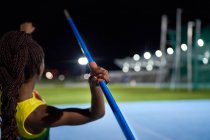 Atleta femminile di atletica leggera che lancia giavellotto nello stadio di notte — Foto stock