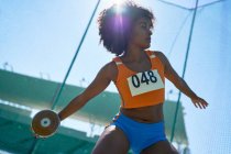 Mujer atleta de pista y campo lanzando disco bajo el soleado cielo azul - foto de stock