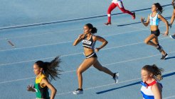 Female track and field athletes running in competition on blue track — Stock Photo
