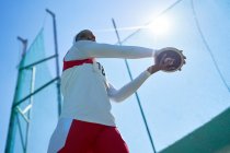 Female track and field athlete throwing discus under sunny blue sky — Stock Photo