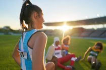 Female track and field athletes resting in stadium grass — Stock Photo