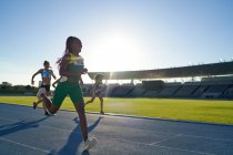 Feliz faixa feminina e atleta de campo ganhando ás na pista ensolarada — Fotografia de Stock