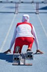 Female track and field athlete in hijab at starting block on track — Stock Photo